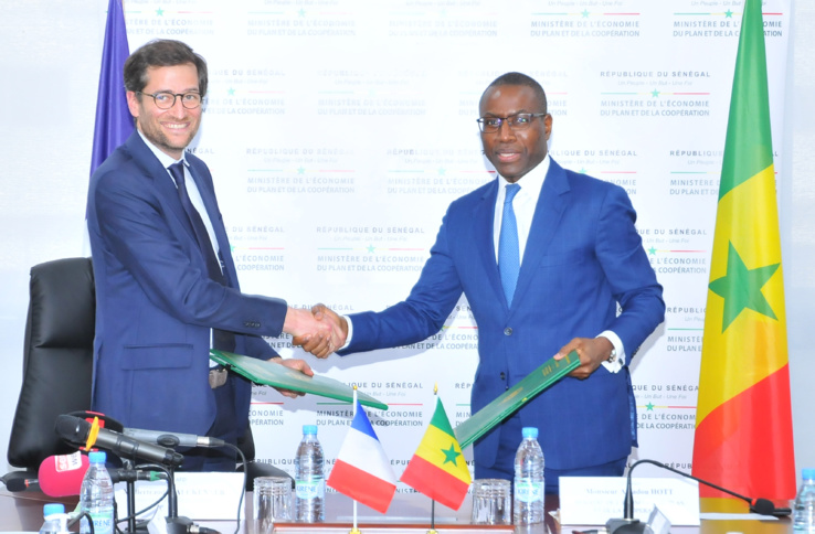 Echange de document entre Amadou Hott, Ministre de l’Economie, du Plan et de la Coopération, et Bertrand Walcknaer, Directeur général adjoint de l’AFD, après la signature d’un protocole d’accord visant à renforcer la dynamique entrepreneuriale du Sénégal.