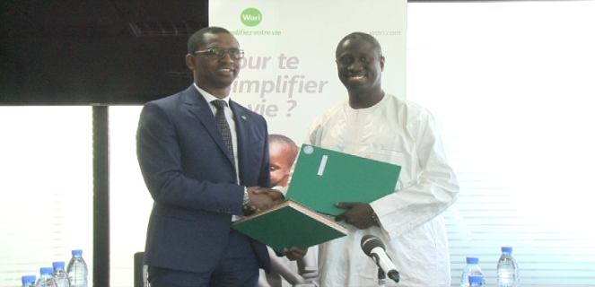 Ibrahima N. E. Diagne, Dg de Gaïdé 2000, à droite en caftan, serrant la main au Président du groupe Wari, un des partenaires de ''Orbus paiement''.