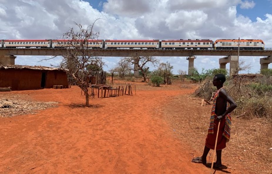 Un jeune homme regarde un train de passagers du chemin de fer à écartement standard survoler sa maison dans le comté de Taita Taveta, dans le sud-est du Kenya. Auteur fourni